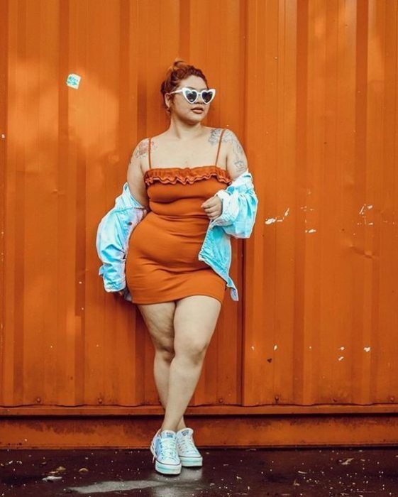 Chica curvy con vestido naranja de tirantes y chaqueta de mezclilla