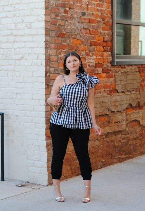 Chica curvy con blusa sin mangas a cuadros y jeans