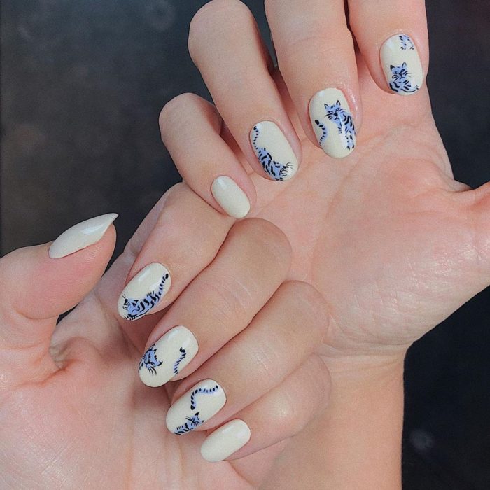 Manicura en tono beige con decorado de gatos en tono gris