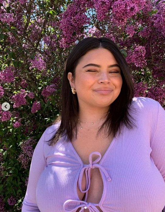 chica curvy de cabello castaño corto usando un suéter morado claro