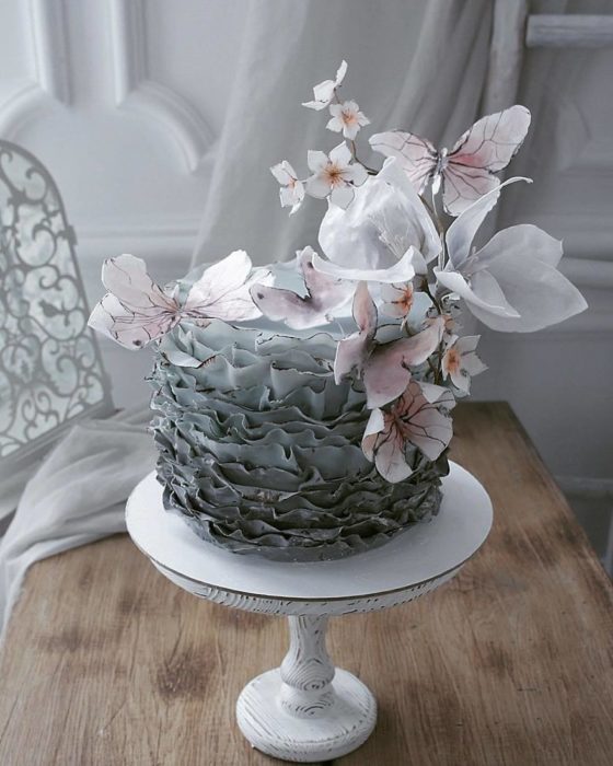 Pastel de volantes verdes con flores blancas