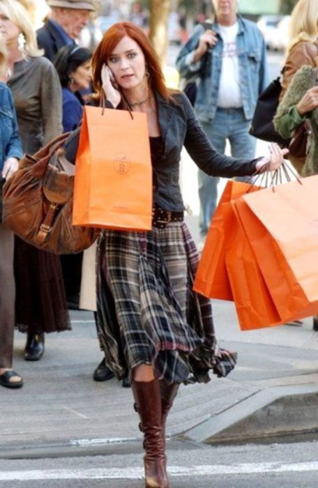 Escena de la película El Diablo Viste a la moda. Emily caminando por la calle sosteniendo varias bolsas en las manos
