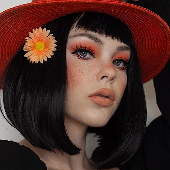 chica con cabello negro, sombrero rojo, sombra de ojos naranja, delineado negro y labial en color neutral