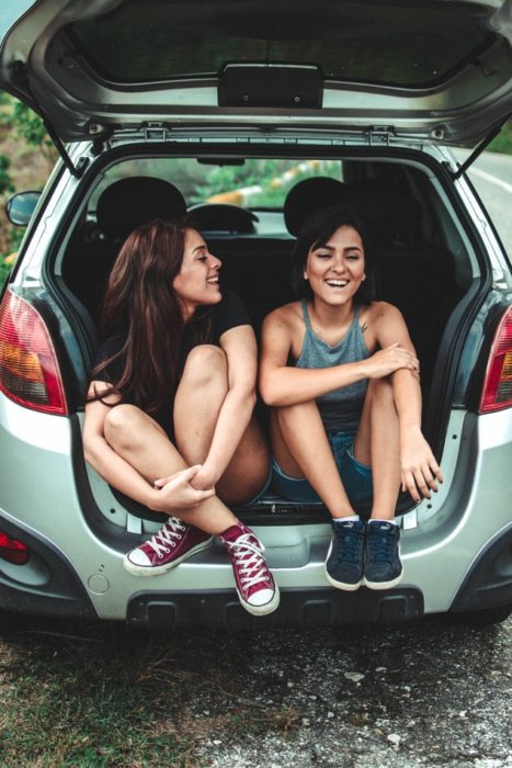 Amigas dentro de un coche, sonriendo y conversando