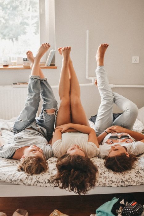 Grupo de amigas recostadas en una cama, conversando