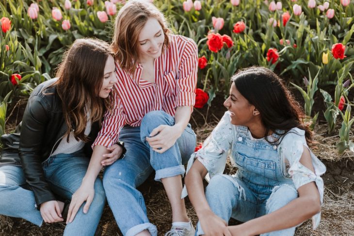 Grupo de amigas riendo y charlando en un campo de tulipanes