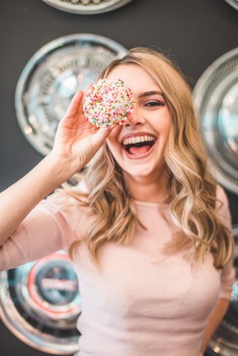 Chica sonriendo mientras juega con una rosquilla