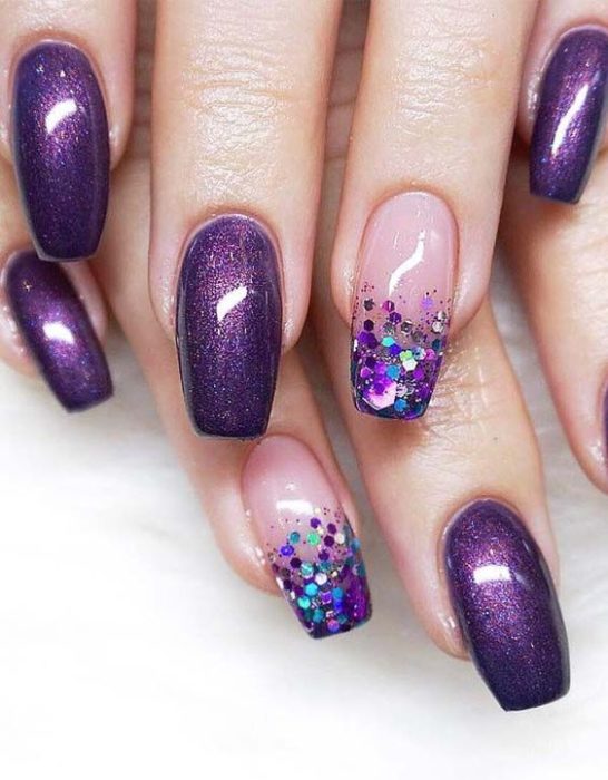 manos de mujer con manicura en tonos morados con efecto glitter y puntas brillantes