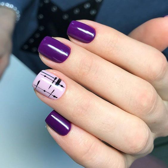 manos de mujer con manicura en tonos morado oscuro y violeta con detalles en negro