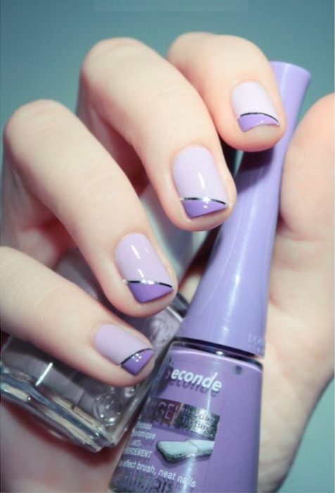 manos de mujer con manicura en tonos violeta y morado con detalles de cintas plateadas
