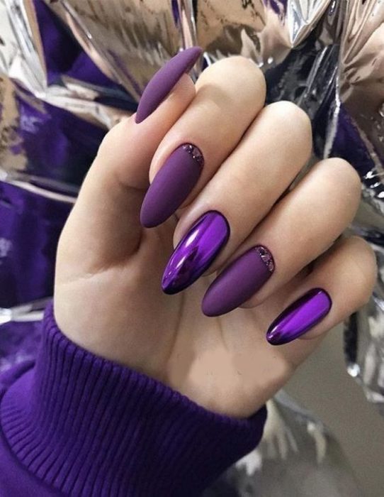 manos de mujer con manicura en tonos púrpura con efecto metalizado y en forma de almendra