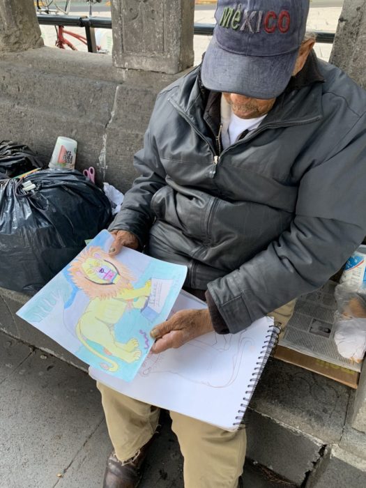 Don Baldemar, abuelo mostrando sus dibujos para vender y sobrevivir ante pandemia