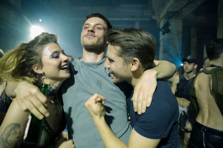 Escena de la serie Beat, amigos abrazados dentro de un bar