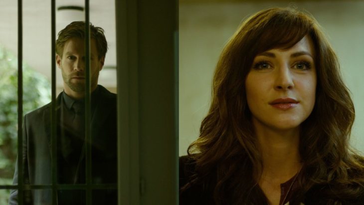 Escena de la serie El perfume, mujer mirando a través de una ventana siendo espiada por un hombre