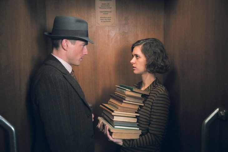 Escena de la serie alemana Babylon Berlin, un hombre y una mujer sosteniendo libros dentro de un elevador