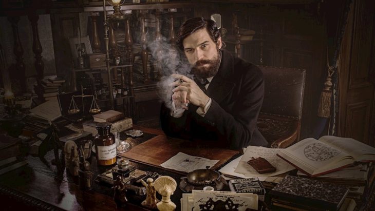 Escena de la serie alemana Freud, con Sigmund Freud sentado frente a un escritorio y fumando un puro