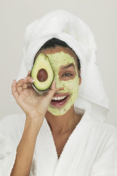 Chica llevando mascarilla de aguacate sobre el rostro y una toalla enredada en la cabeza