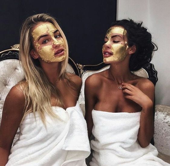 Chicas sentadas en un sofá llevando mascarillas doradas en el rostro