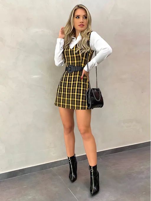 Mujer rubia tocándose el cabello y posando con traje amarillo de cuadros