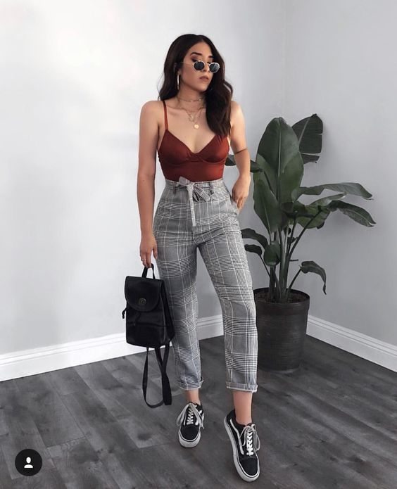 Chica posando con gafas de sol, blusa roja y pantalón gris de cuadros