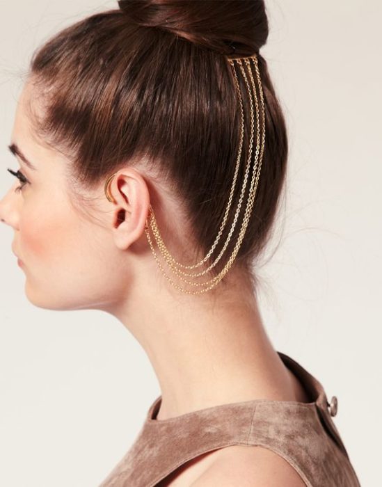 Chica con cabello recogido en chongo y con accesorio de cadena que va desde la oreja