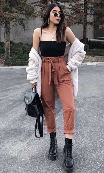 Chica con estilo grunge con top negro y paper bag pants rosas con botas dr martens