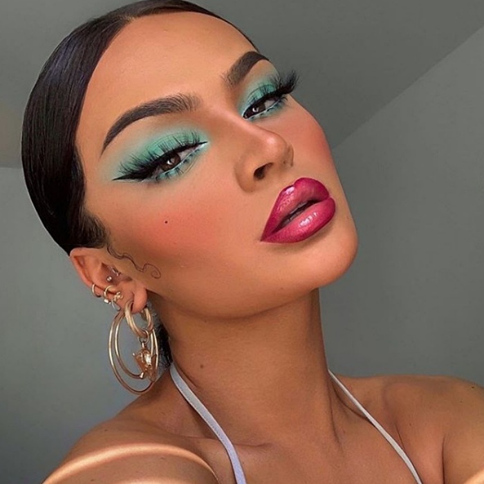 chica morena con maquillaje en color aqua y labial fucsia