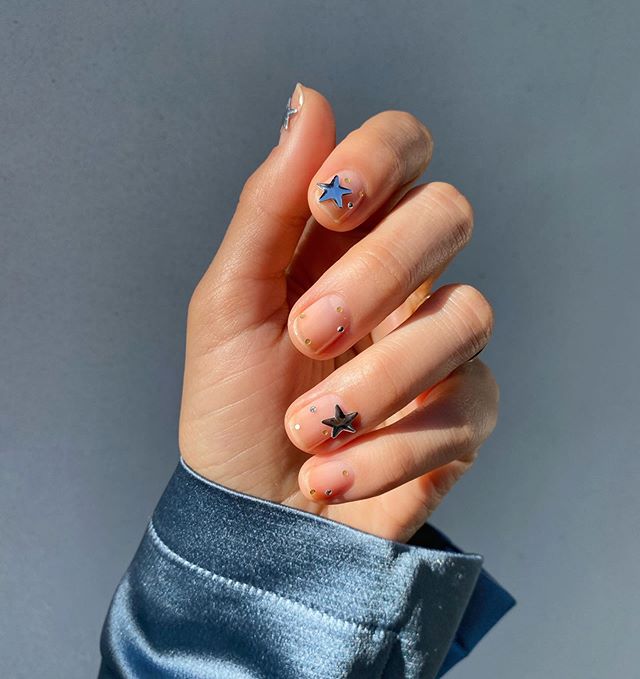 Diseños de uñas de Betina Goldstein con estrellas grandes en el dedo medio e índice 