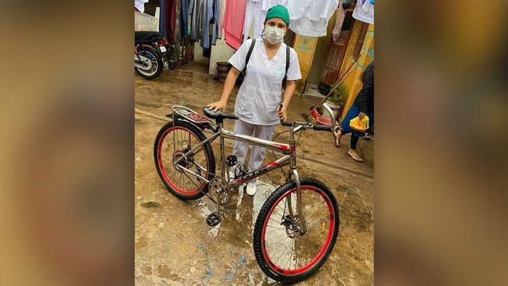 Enfermera sosteniendo su bicicleta después de regresar de trabajar en el hospital 