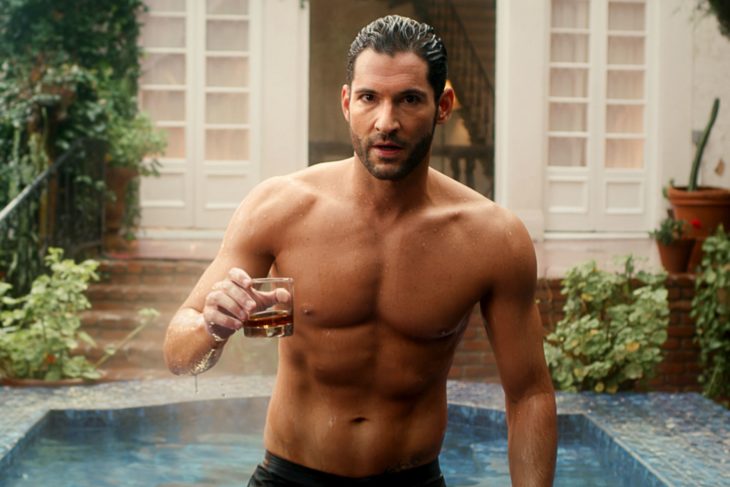 Tom Ellis, actor y protagonista de Lucifer, saliendo de la piscina sin camisa y sosteniendo un vaso de vidrio con whisky.