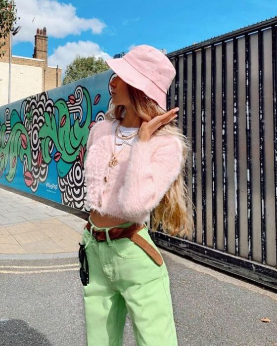 Chica posando para una foto en plena avenida junto a una pared llena de dibujos