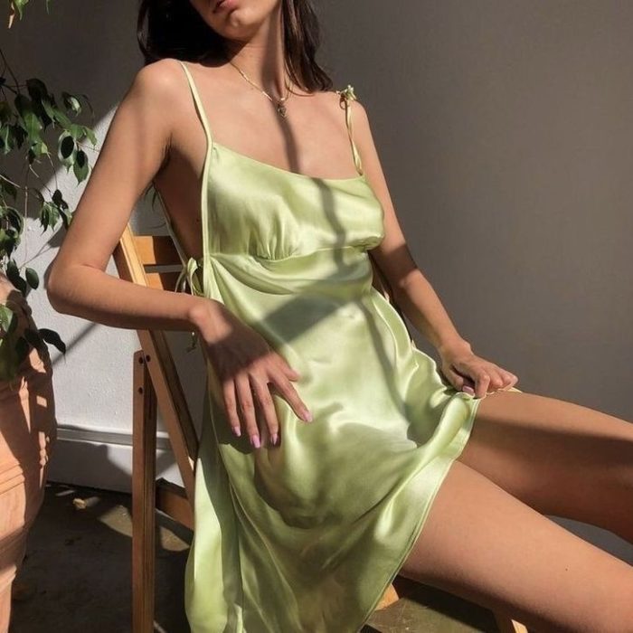 chica con vestido de satén de tirantes sentada en una silla