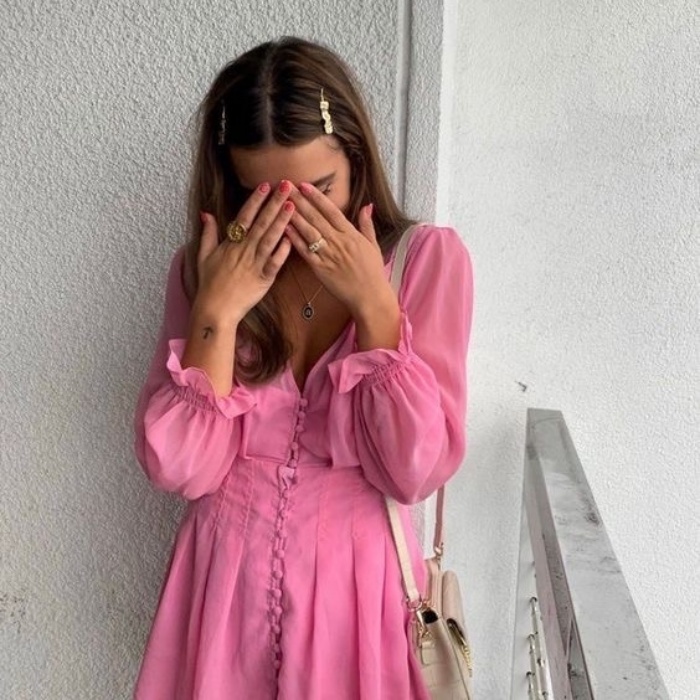 chica con cabello castaño, broches en el cabello y usando un vestido rosa de manga larga con vuelos