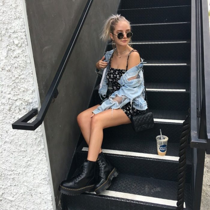 chica con vestido negro de lunares blancos, chamarra de mezclilla con lentes de sol y botas de cuero negras