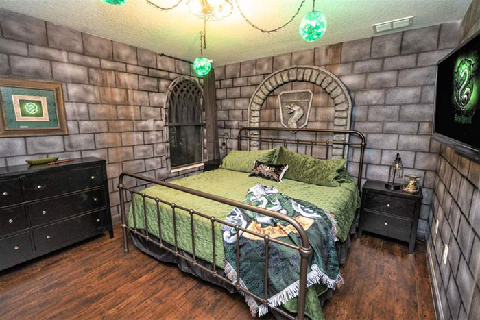 Habitación decorada con papel tapiz en forma de ladrillos grises con cobijas verdes