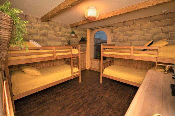 Recamara decorada con papel tapiz de ladrillo, literas de madera y cobijas amarillas