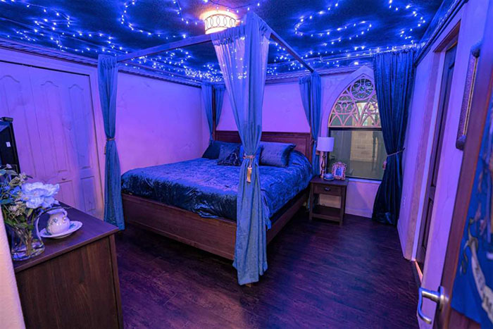 Habitación decorada con luces azules y cortinillas alrededor de la cama