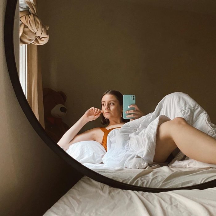 Chica tomando selfie con su celular del reflejo del espejo