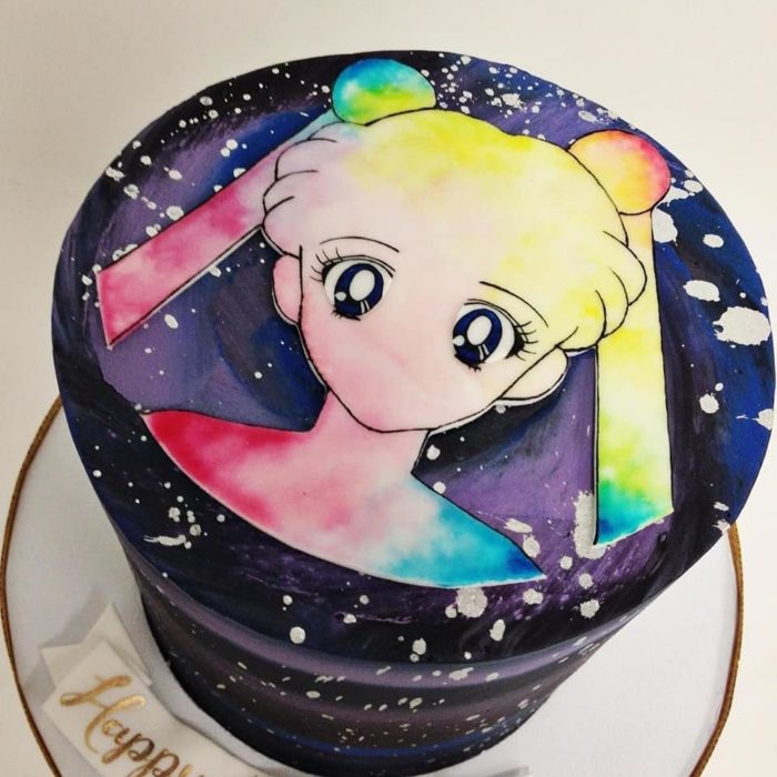 Pastel de Sailor Moon con base de fondant negra, y el rostro de Serena en blanco y tonalidades de arcoíris