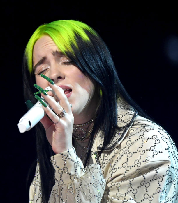 Billie Eilish cantando, cabello verde neón y negro