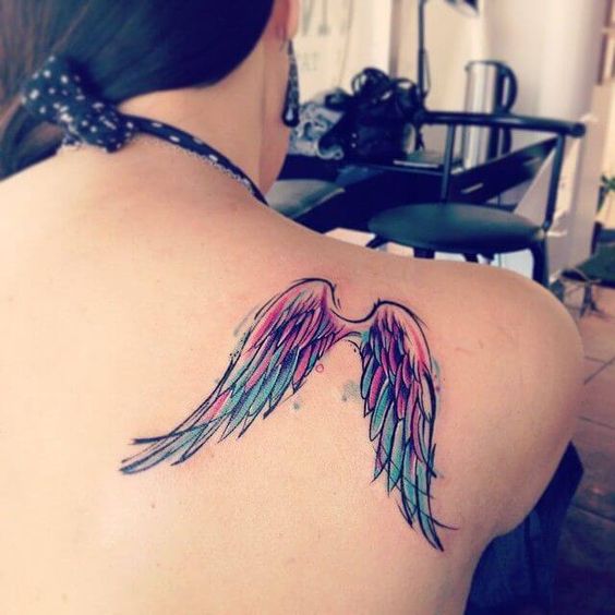 Tatuaje de alas con color rosa y morado en omóplatos de mujer