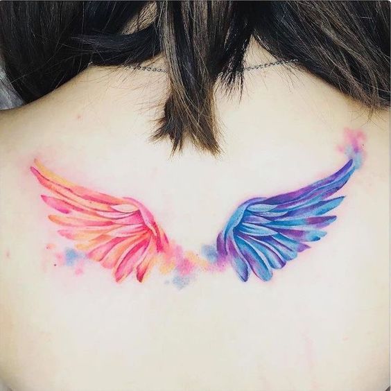 Tatuajes de alas coloridas en espalda de mujer