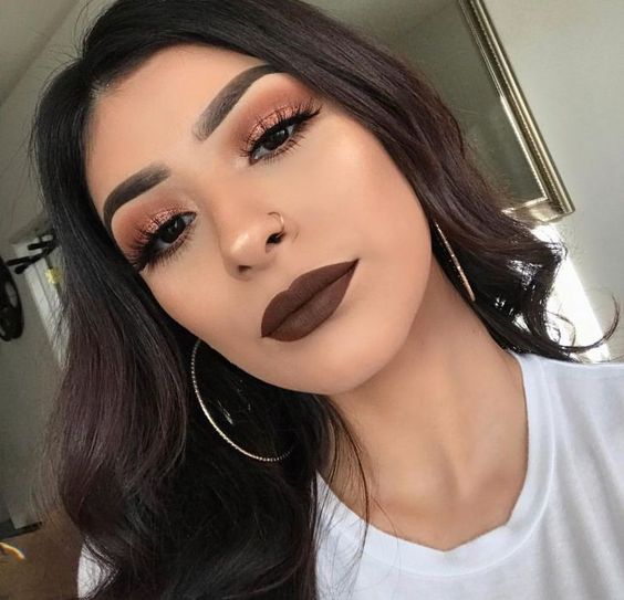 Chica latina de cabello largo y negro suelto usa labial marrón 