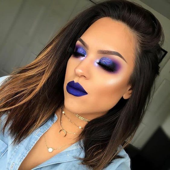 Mujer morena con melena castaña usa maquillaje de ojos extravagante y labial azul