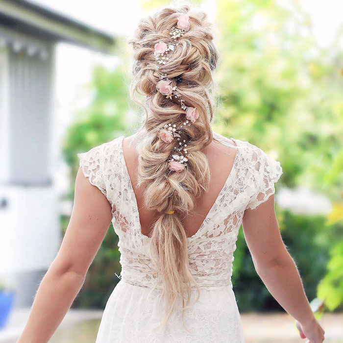 Chica rubia de cabello largo con trenza esponjosa con flores rosas