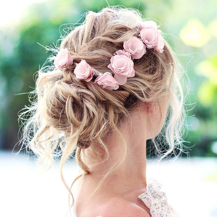 Mujer rubia con recogido suelto con flores rosas
