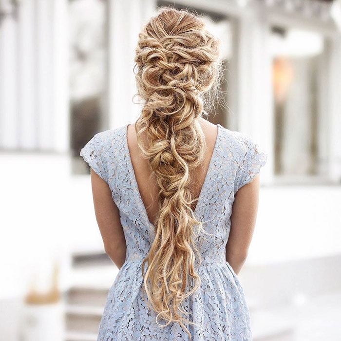 Mujer rubia con trenzas con mucho volumen con flores azules