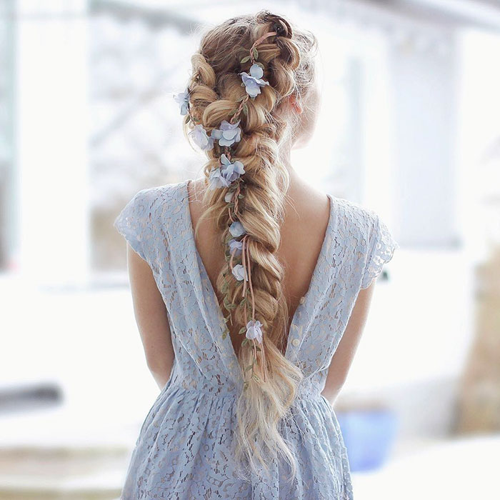 Mujer rubia con trenzas con mucho volumen con flores azules