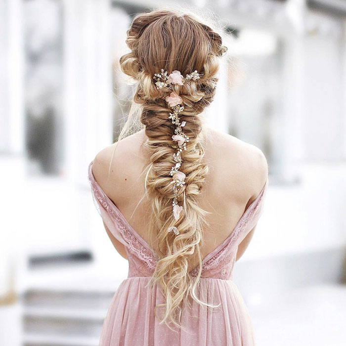Chica rubia de cabello largo con trenza esponjosa con flores rosas