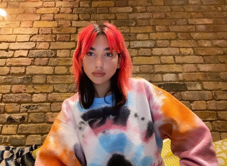 Dua Lipa con el cabello teñido en colores rosas y rojo en la parte inferior